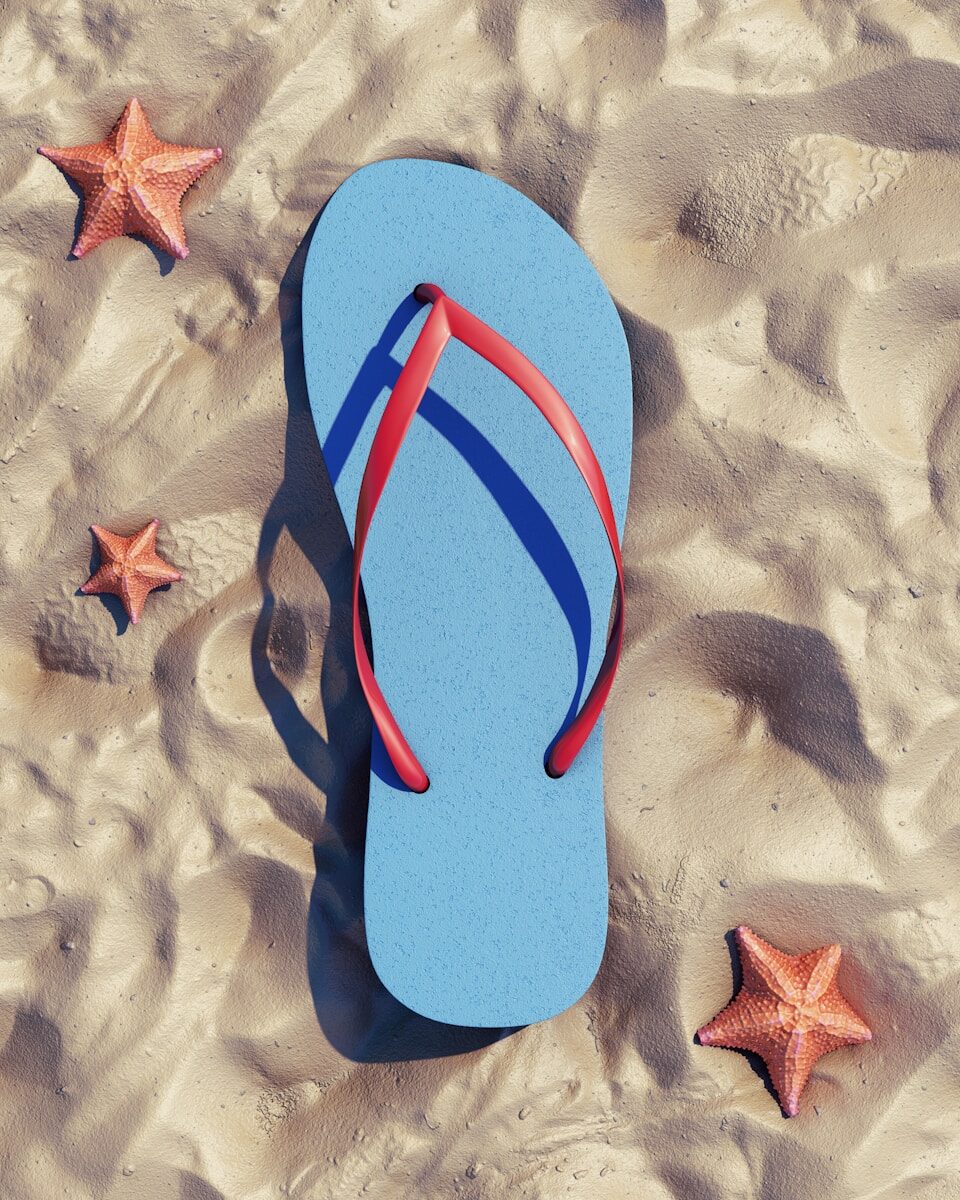 Summer flip-flop and starfish on warm sand